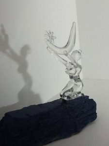 a glass sculpture of a person kneeling and holding a moon and a star
