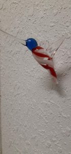 a blown glass red, white, and blue hummingbird